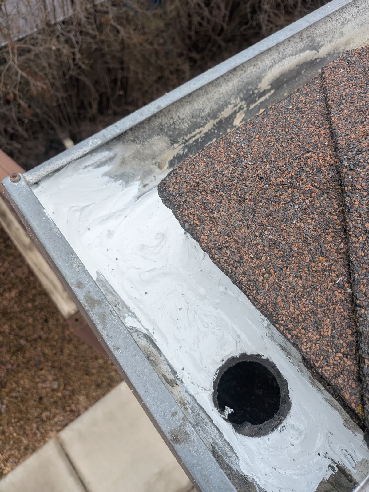 Fresh sealant on gutter corner and downspout opening